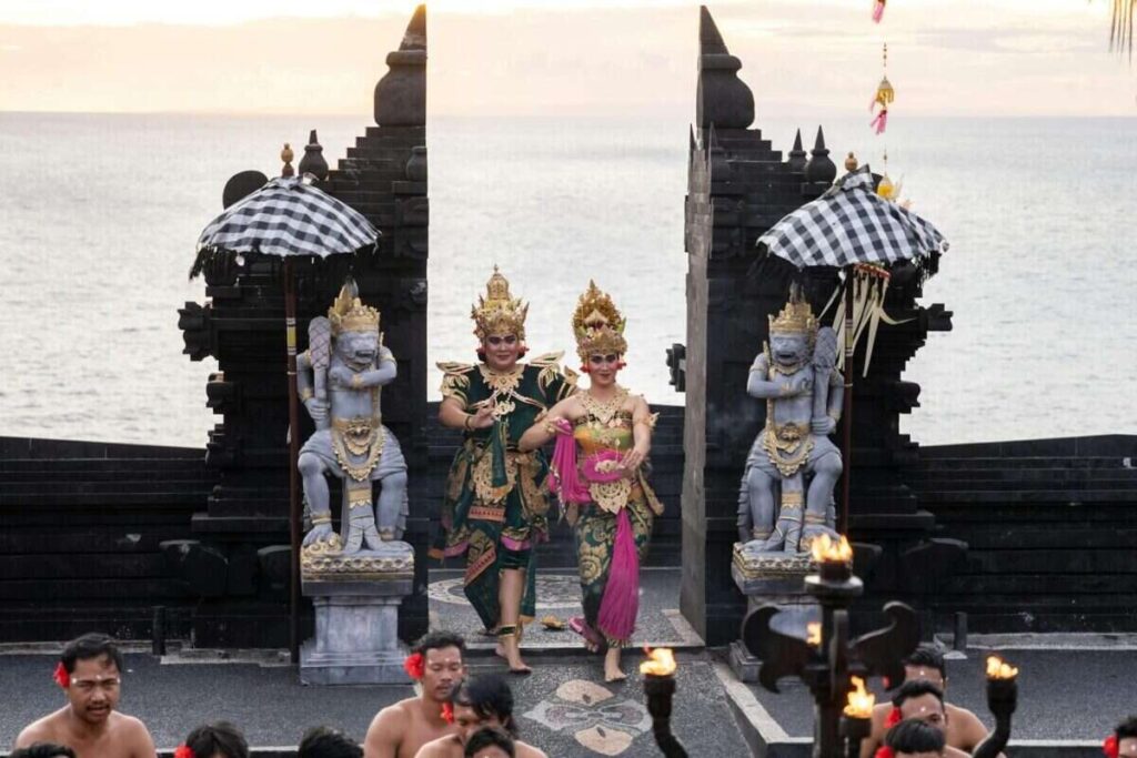 Balinese dancers perform at the iconic Uluwatu Temple during sunset, showcasing vibrant traditional attire.