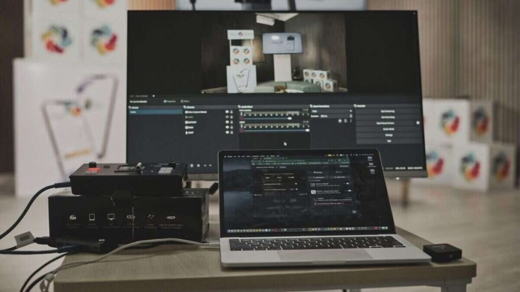 Multimedia setup featuring a laptop and a large monitor in a tech-savvy workspace.