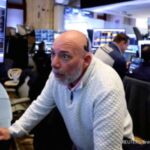 Layar monitor menampilkan grafik pergerakan bursa saham Amerika Serikat yang melemah di Wall Street.