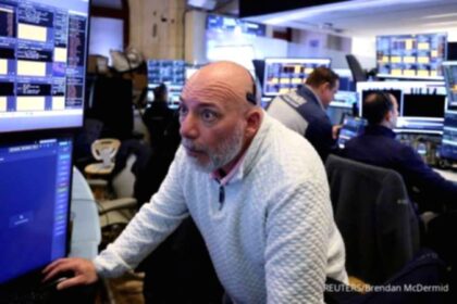 Layar monitor menampilkan grafik pergerakan bursa saham Amerika Serikat yang melemah di Wall Street.