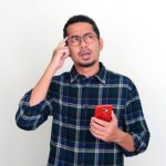 Ilustrasi aplikasi Kredivo di layar ponsel pintar dengan latar belakang perkantoran di Jakarta.