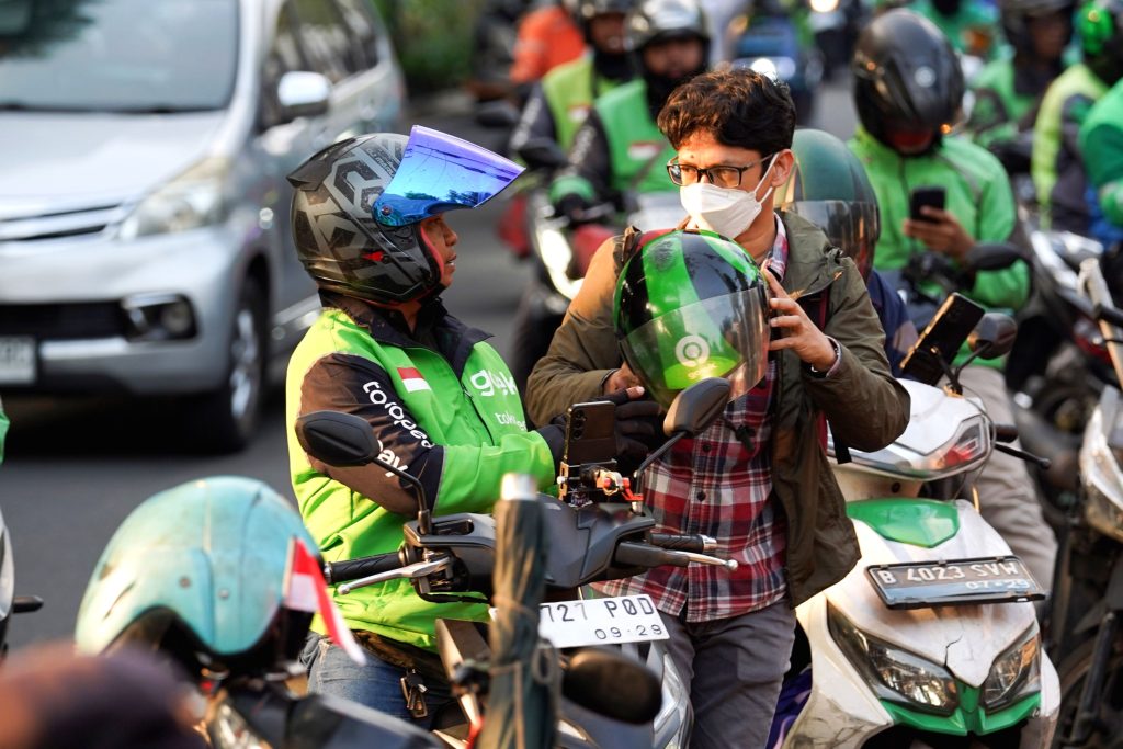 Ilustrasi pengemudi ojek online sedang melihat ponsel di pinggir jalan kota