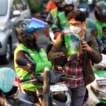 Ilustrasi pengemudi ojek online sedang melihat ponsel di pinggir jalan kota
