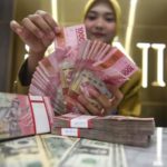 Papan informasi nilai tukar mata uang yang menunjukkan pelemahan rupiah terhadap dolar AS