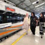 Kereta api Indonesia melintas di jalur rel dengan latar belakang pemandangan perkotaan