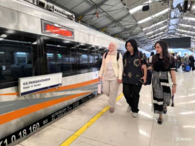 Kereta api Indonesia melintas di jalur rel dengan latar belakang pemandangan perkotaan